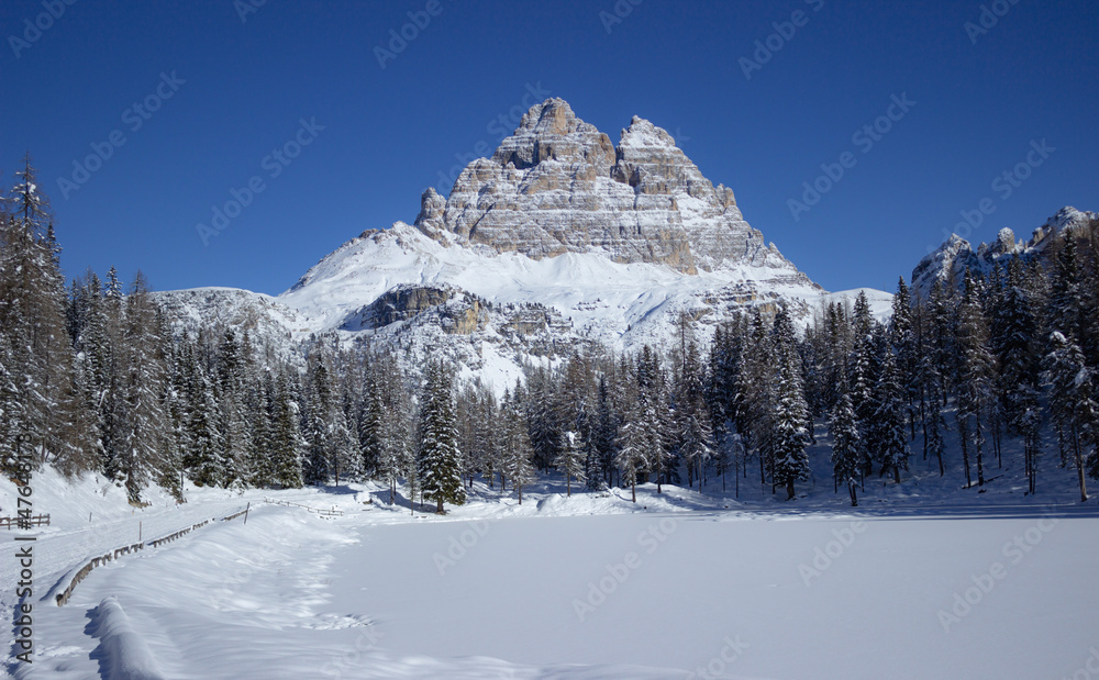 Winter background. Small frozen and snow-covered lake with mountain background. Holiday and christmas concept. Antorno lake, Italy