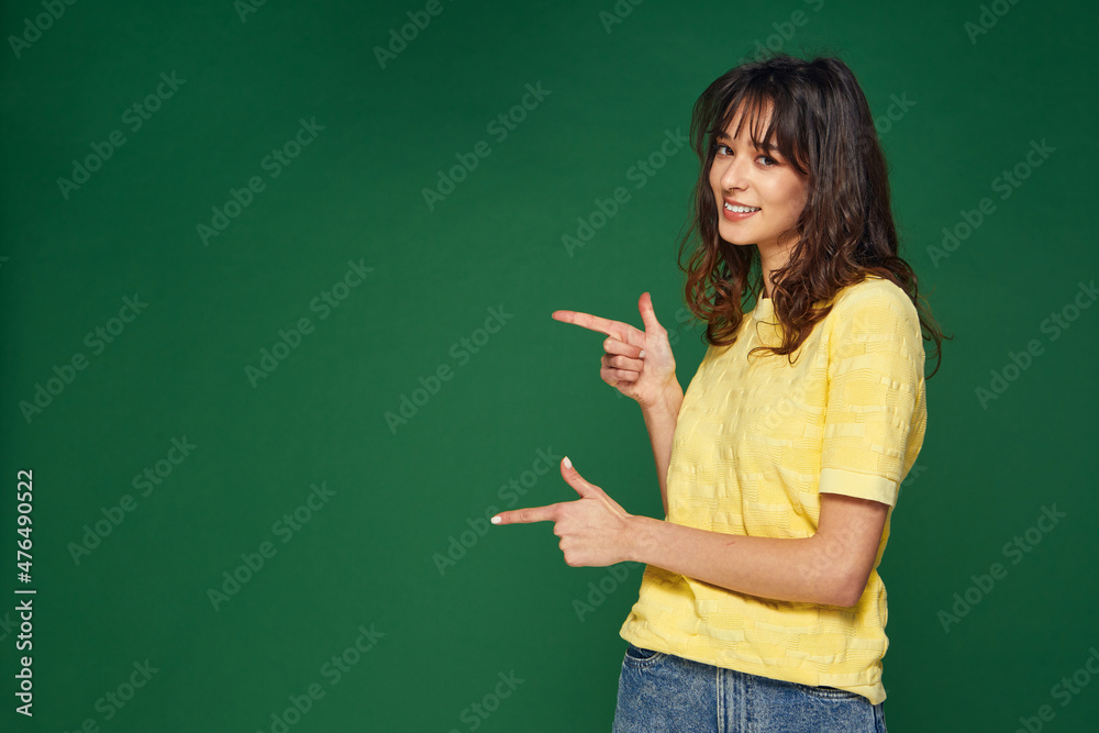 Modern beautiful young girl point to side showing on empty space on green background for sale offer, advertising Modern beautiful young girl point to side showing on empty space on green background for sale offer, advertising