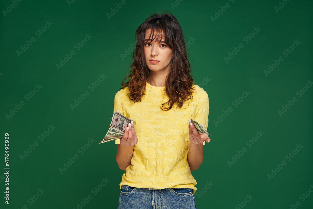 Financial crisis, money problems. Frustrated young girl holding cash banknotes, worried about debt, credit, loan, taxes