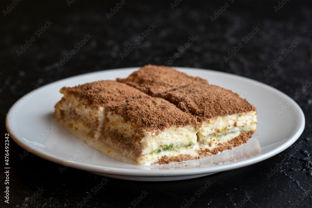 Cold baklava on a dark background. Turkish sweet dessert concept. plate of sliced forest fruit cake. Plate of cold milk baklava. Mediterranean bakery. close up. selective focus. soguk baklava Cold baklava on a dark background. Turkish sweet dessert concept. plate of sliced forest fruit cake. Plate of cold milk baklava. Mediterranean bakery. close up. selective focus. soguk baklava