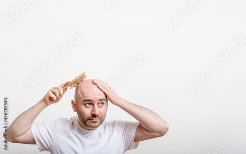 confused bald man with hair brush