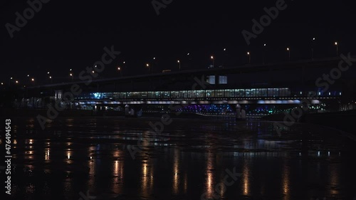metro bridge the train arrives at the station night view of the city river bound by ice shining with neon lights in the dark blue sky  water glow moscow fog reflection
