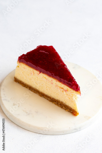 Cheesecake on white background. Greek sweet dessert concept. plate of sliced cheesecake. Cheesecake with raspberry gel filling. Mediterranean bakery. close up. selective focus. Vertical view.