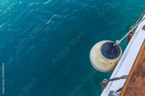 A white, round sailboat fender hanging over turquoise colored Mediterranean Sea. © Arzi
