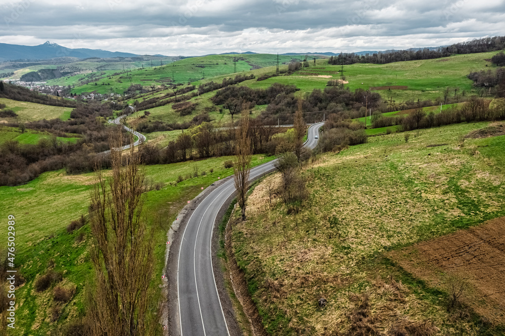 Aerial view of a narrow winding road, through the beautiful wooded Carpathians, amazing spring landscape, outdoor tourist background, Transcarpathia, Ukraine