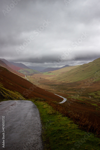 Landscape of mountain road leading into the distance under a heavy sky. Lake District, England