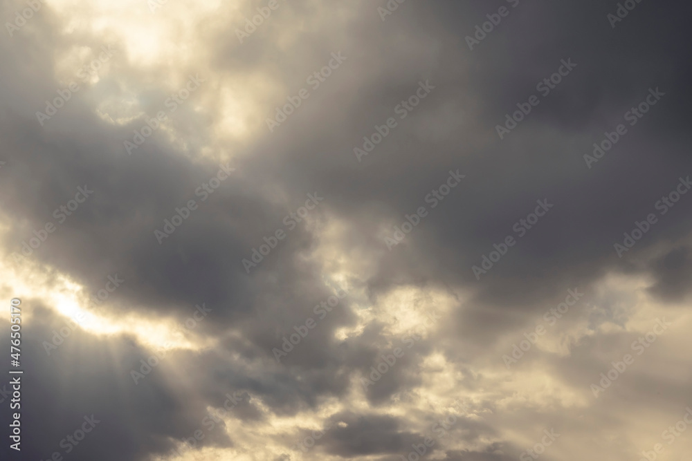 Dramatic dark cloudy sky with sun rays. Nature background.