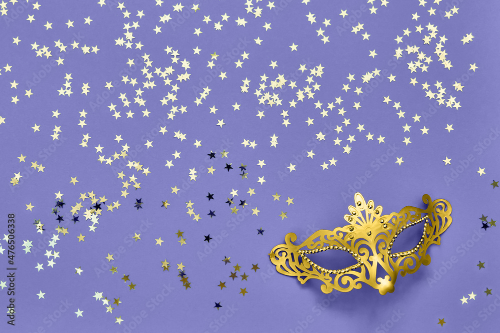 Fototapeta premium Golden carnival mask and golden stars on lilac very peri background. Carnival celebration concept.