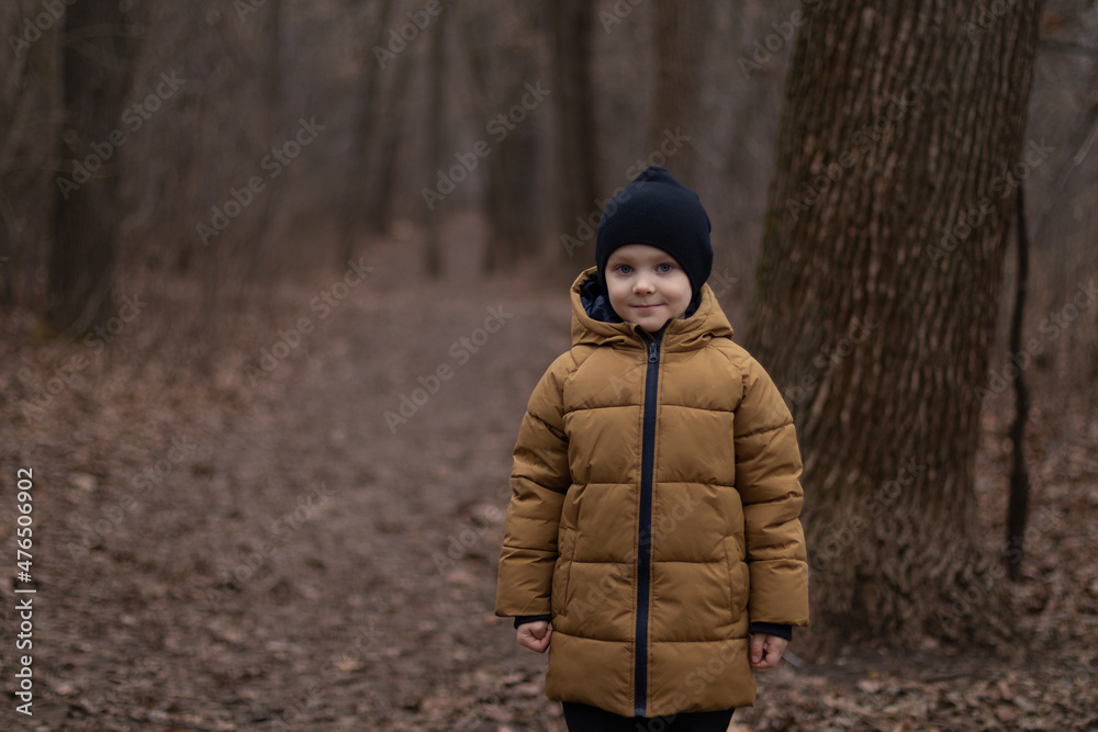 cute boy on a cloudy day. boy looking at camera and smiling. winter without snow concept 