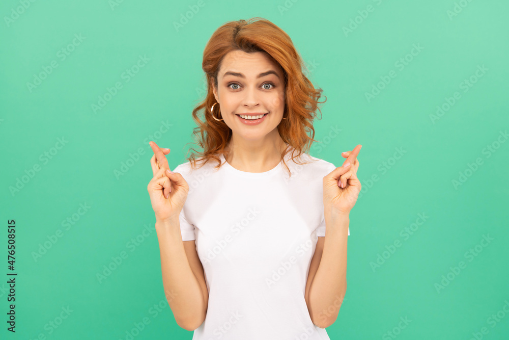 happy redhead woman with curly hair cross fingers making a wish on blue background, wish happy redhead woman with curly hair cross fingers making a wish on blue background, wish