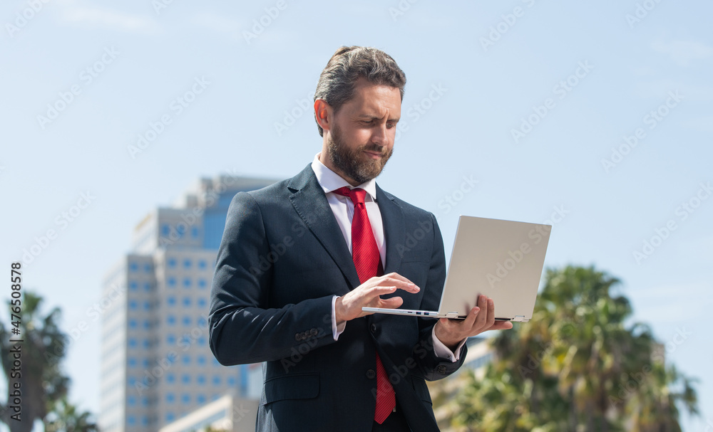 confident man in elegant suit checking email on pc outside, agile business confident man in elegant suit checking email on pc outside, agile business