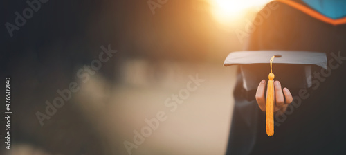 graduates holding black hats with yellow tassels standing with raised diploma in hand over sunset,Concept education congratulation. Graduation Ceremony ,Congratulated the graduates in University.