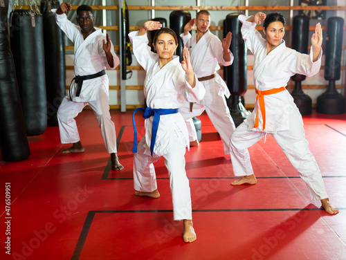 Group of people, Caucasian, African-american, Hispanic, Asian people in kimono doing kata moves in gym.