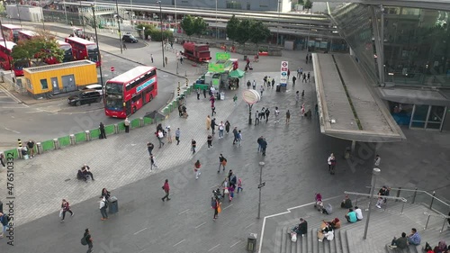 Busy pedestrian zone at modern Stratford transport terminal. Group of typical red double deckers. London, UK.