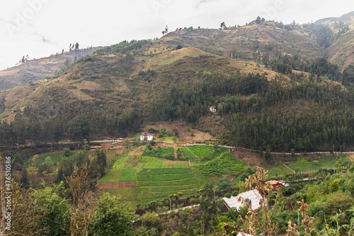 High mountain scenery with crop fields and small houses covered with fog in the Ecuadorian highlands. South America.