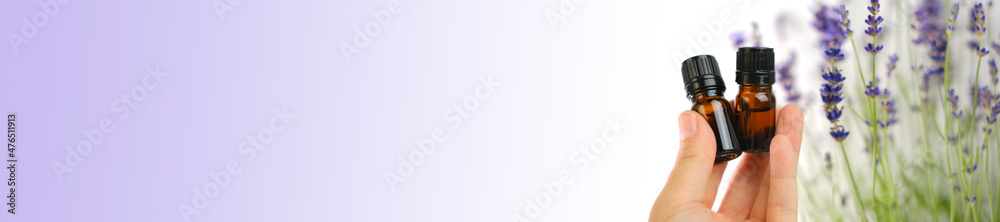 Lavender essential oil banner. Bottles of essential oil in a woman's hand and lavender flowers on a purple background. Cosmetics with lavender extract banner. Lavender essential oil banner. Bottles of essential oil in a woman's hand and lavender flowers on a purple background. Cosmetics with lavender extract banner.