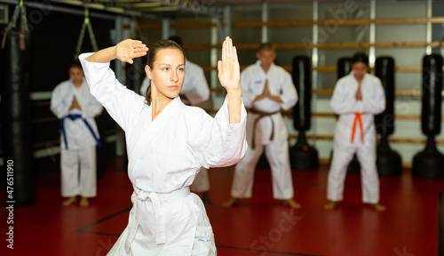 Woman in kimono is practicing karate moves at gym
