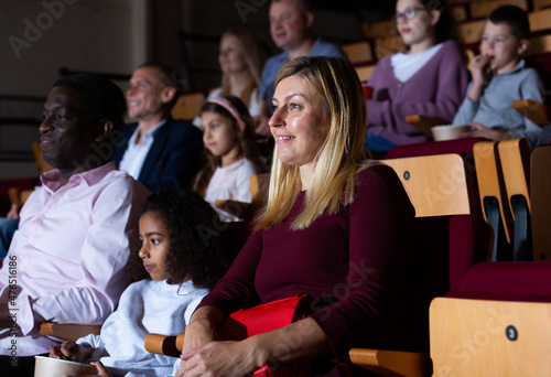 caucasian mother, african father and their children sitting at movie in auditorium