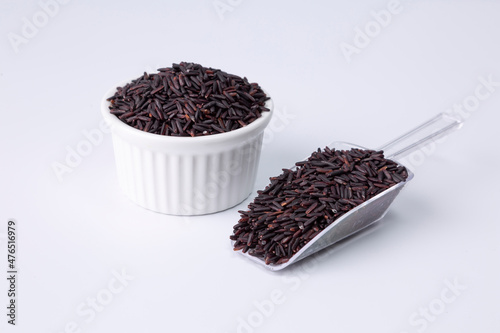 riceberry rice in a white bowl and plastic spoon on white background