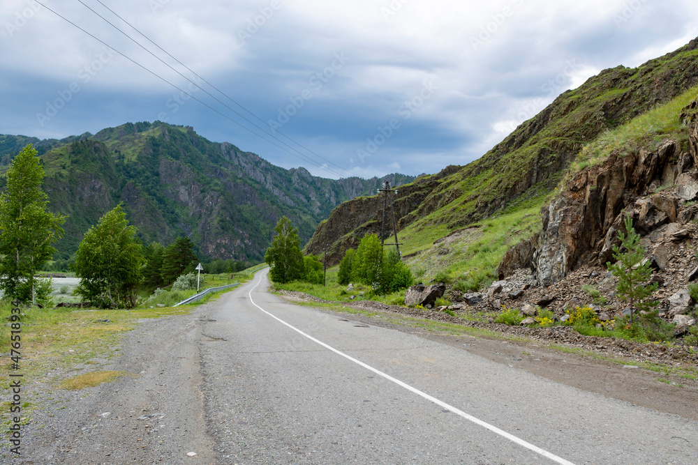 Fototapeta premium The paved road between steep mountain peaks goes into the distance