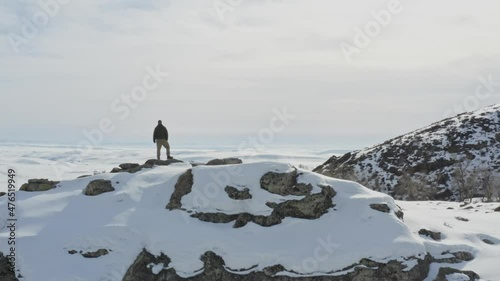 Unrecognizable man on snow covered hill enjoying winter landscape. Aerial circling photo