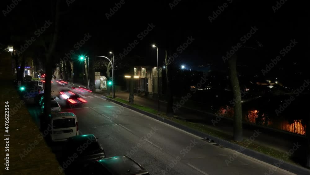 italian town night traffic timelapse - passing vehicles stop at traffic light and pedestrians cross the road