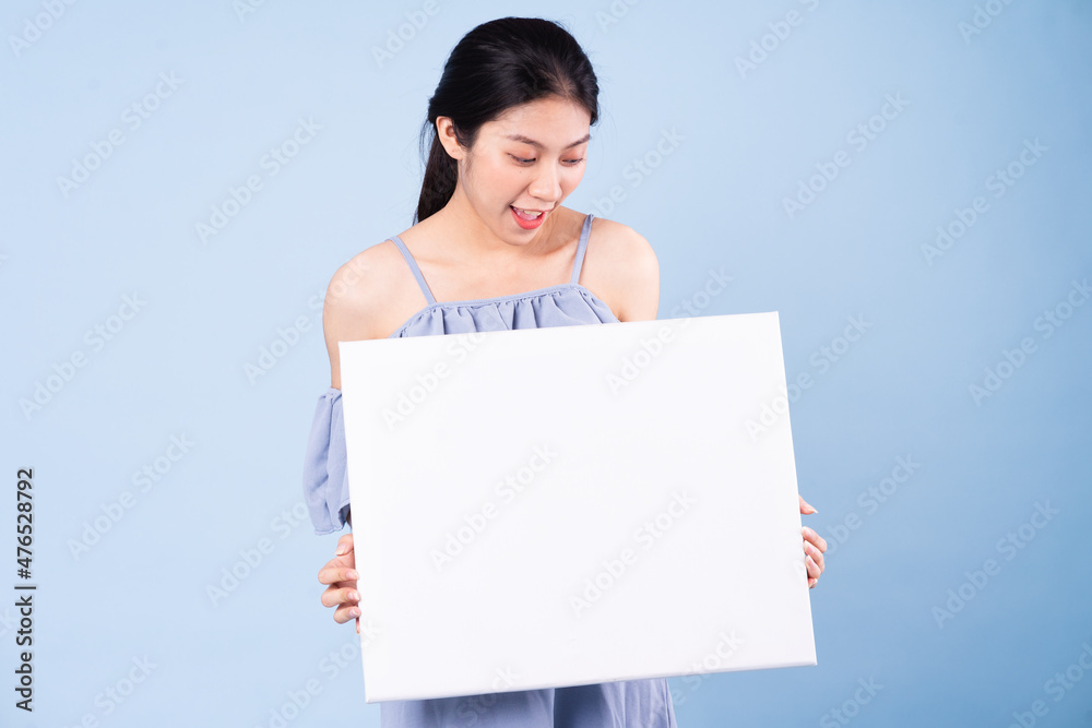image of asian girl holding white board, isolated on blue background image of asian girl holding white board, isolated on blue background