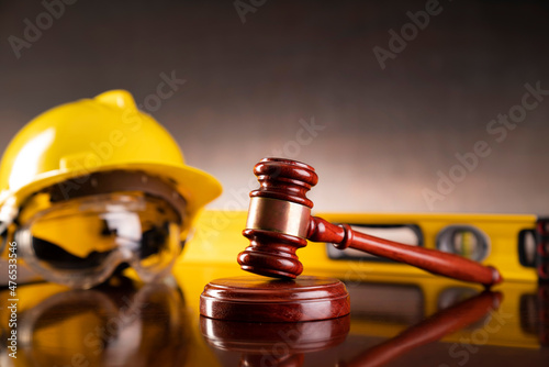 Labour law and builiding law concept.  Gavel and yellow crash helmet on the shining lawyer desk. photo