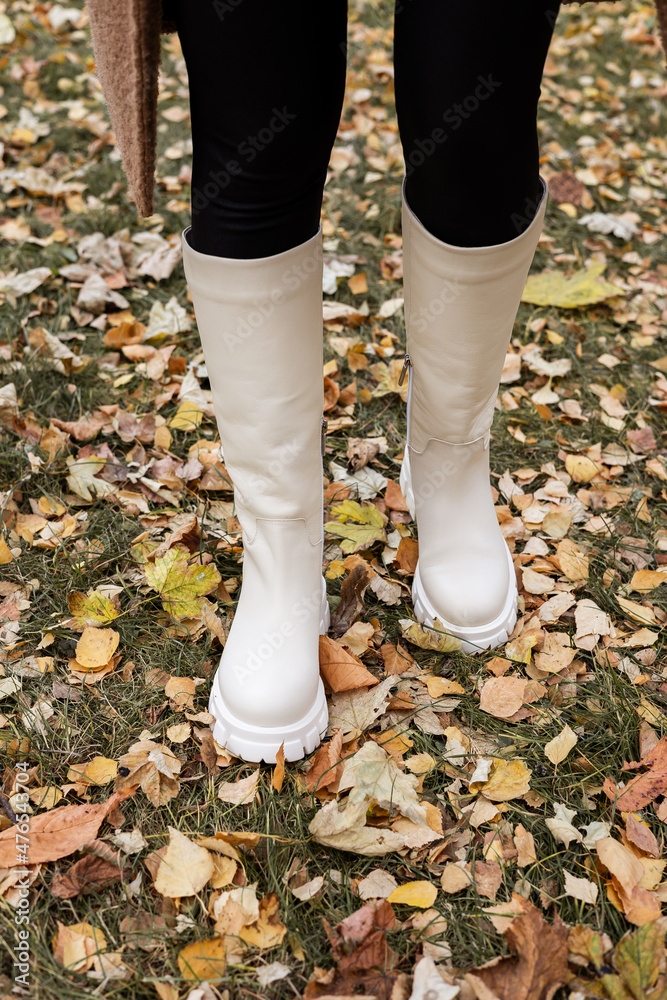 Trendy beige trumpet boots on a female leg, close-up, fashionable. New collection of women's shoes with genuine leather