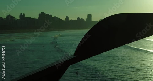 Dawn in santos sp brazil east coast port city oscar niemeyer architecture with surfers background and foreground rocks and coconut trees photo