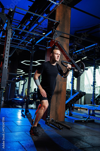 Attractive adult man doing exercises and lifting weights in the gym. Sports training in the gym