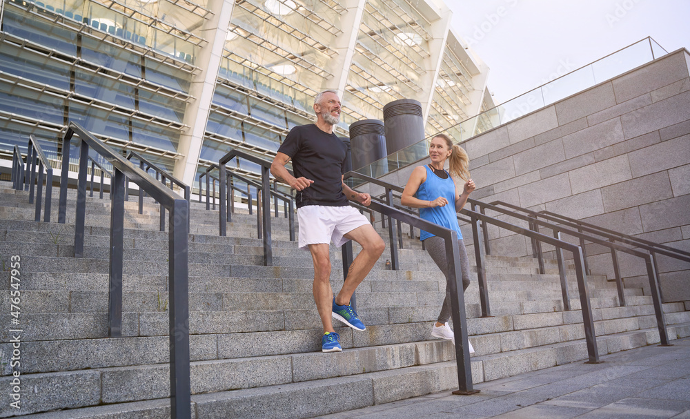 Mature couple, man and woman in sportswear making a workout session together, exercising on staircase outdoors Mature couple, man and woman in sportswear making a workout session together, exercising on staircase outdoors