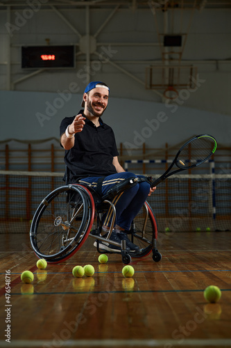 Young man in wheelchair playing tennis on court © Georgii