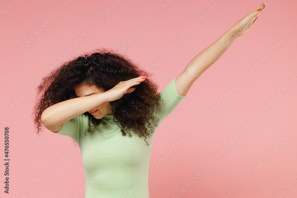 Young curly latin woman 20s years old wear mint t-shirt sunglasses doing dab hip hop dance hands move gesture youth sign hide cover face isolated on plain pastel light pink background studio portrait Young curly latin woman 20s years old wear mint t-shirt sunglasses doing dab hip hop dance hands move gesture youth sign hide cover face isolated on plain pastel light pink background studio portrait