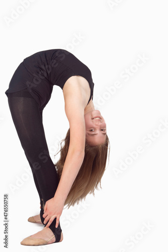 Full Length Portrait of Standing Straight Caucasian Rhythmic Gymnast Sportswoman In Training Outfit During Her Backward Shape Stretching Against White.