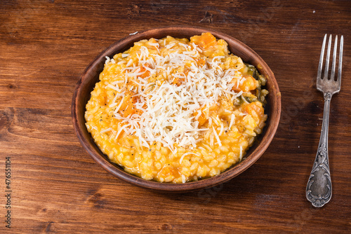 Serving of pumpkin risotto in a plate sprinkled with grated Parmesan cheese