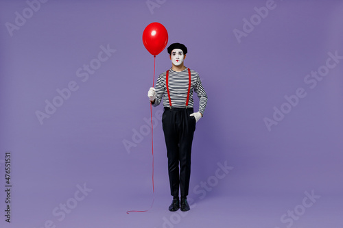 Tableau sur toile Full size body length vivid young mime man with white face mask wears striped shirt beret holding colorful air inflated helium balloon isolated on plain pastel light violet background studio portrait