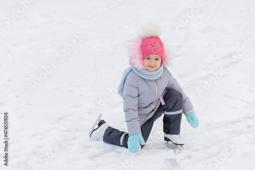 little girl learning ice skating in park on rink. children winter sport. outdoor games, pastime wintertime. kids with skates on cold freezing day. Snow outdoor fun for child. Christmas family vacation