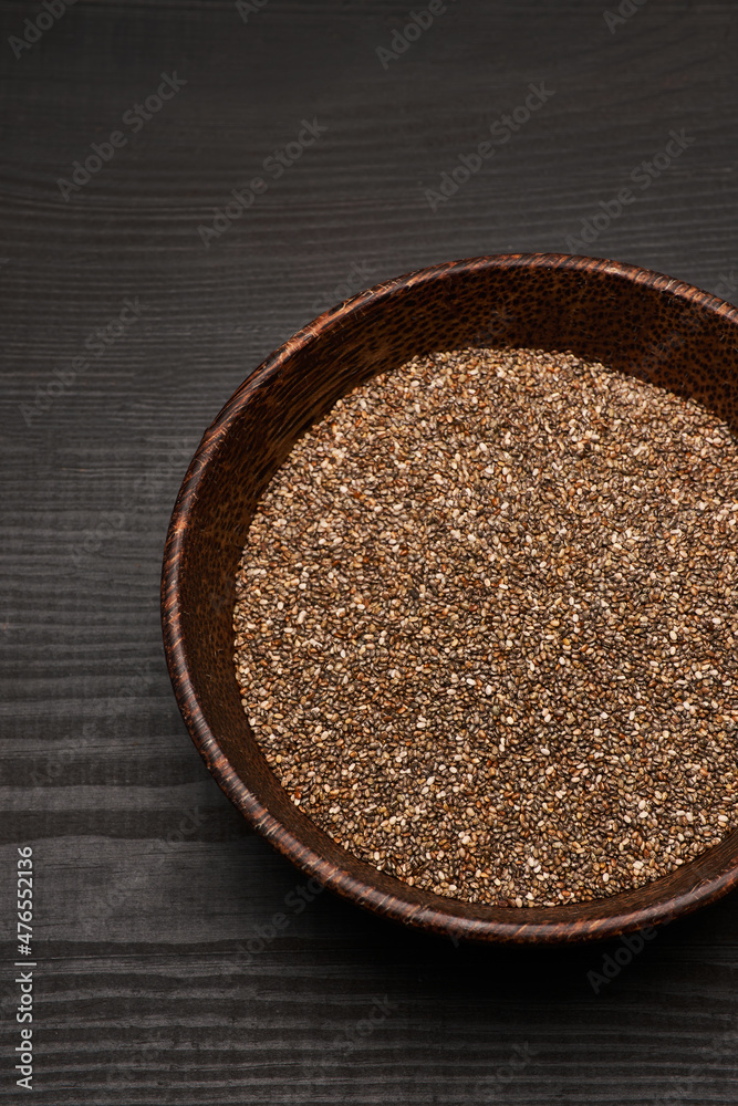 Organic natural chia seeds in wooden bowl close-up on dark wooden background or table Organic natural chia seeds in wooden bowl close-up on dark wooden background or table