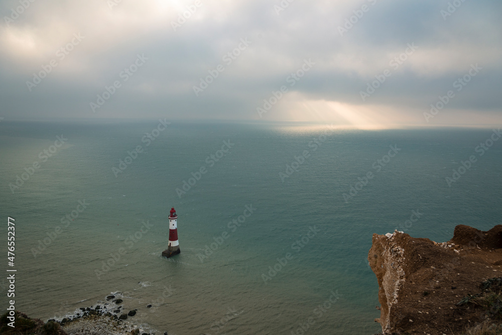 Sunlight breaking through the thick December clouds over Beachy Head lighthouse on the East Sussex coast, south east England