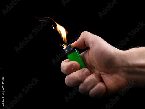 male hand using green lighter with flashflame and sparks isolated on black background photo