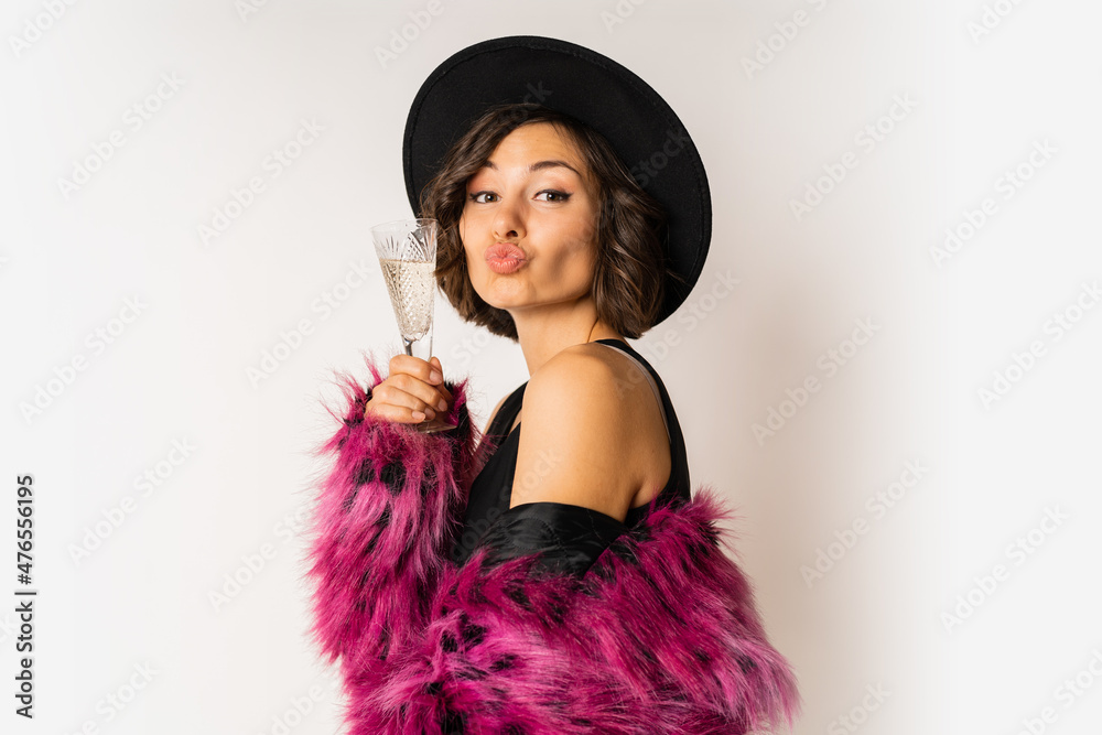 Happy selebrating woman in stylish fur coat holding glass of shampagne , wearing pink fur coat and black party dress. posing over white background. Happy selebrating woman in stylish fur coat holding glass of shampagne , wearing pink fur coat and black party dress. posing over white background.