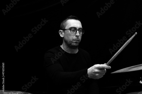 Young beraded man in glasses playing drums	 photo