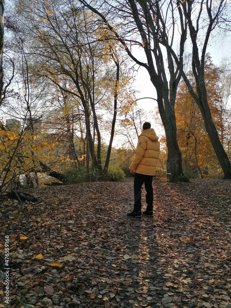 A man walking in a yellow down jacket in an autumn forest