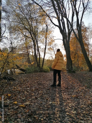 A man walking in a yellow down jacket in an autumn forest © ChrisOvergaard