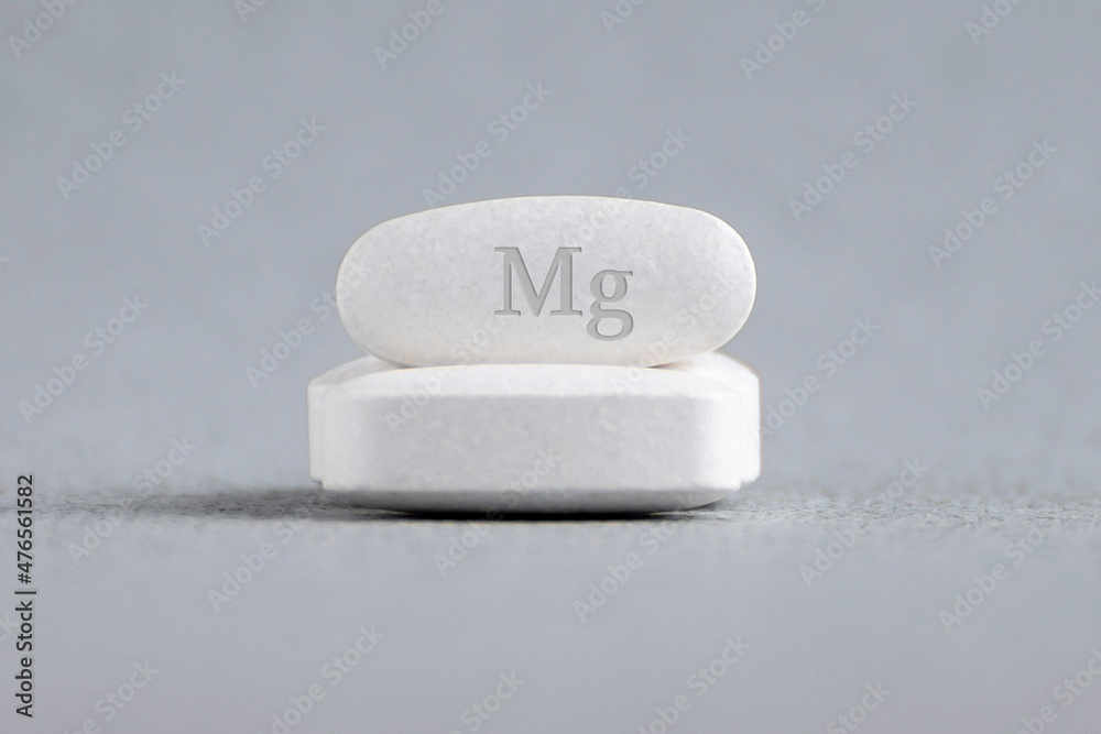Tablets , vitamins with the abbreviation Mg ( magnesia, macro element magnesium ) on a light background. Copy space. Tablets , vitamins with the abbreviation Mg ( magnesia, macro element magnesium ) on a light background. Copy space.