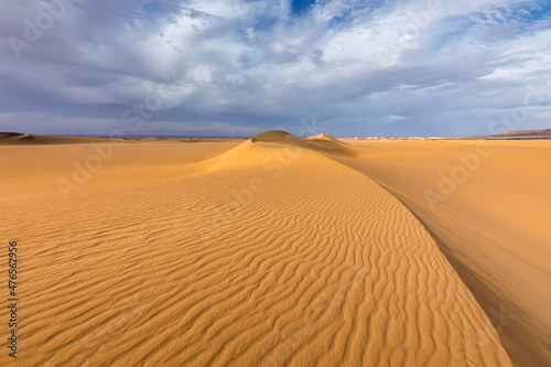 Sunset over the sand dunes in the desert. Arid landscape of the Sahara desert.
