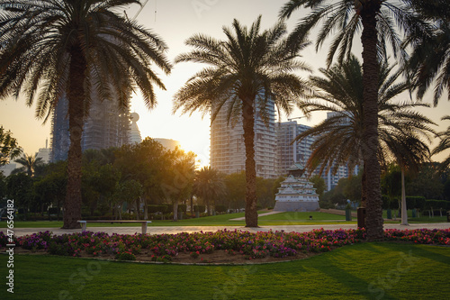 Alley with green lawn and trees in the Zabeel park, Dubai, UAE. View of the modern Dubai skyline from the approach highway to the Zabeel Palace, Dubai, United Arab Emirates photo