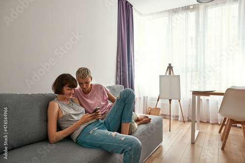 Young lesbians watch on smartphone on sofa at home © Svitlana