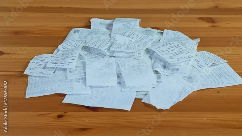 Paper receipt pile. Shopping receipts on a wooden table. Stop motion photo
